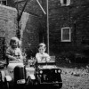 Richard and Robert Bond in pedal cars in Six Bells yard