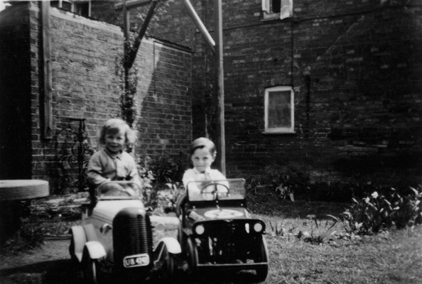 Richard and Robert Bond in pedal cars in Six Bells yard