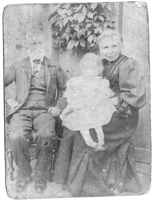 early picture of elderly couple with infant on knee