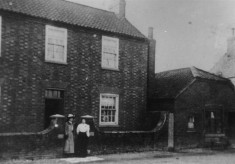Ladies in front of farmhouse and butcher's shop on High Street