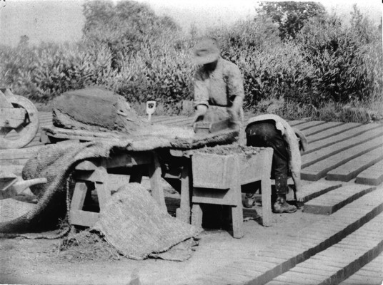 Adding the raw brick to the drying stacks.