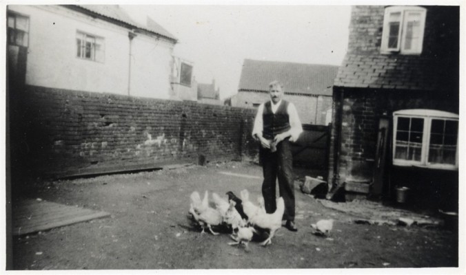 Reg Barke with chickens in yard at Bottesford Coffee House, during WW2