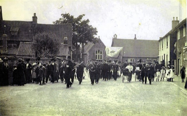 Bottesford Village band marching in Church Street ahead of the Bottesford Friendly Society members carrying their marching banner, on the inauguration of Edward Prince of Wales on the 13th July 1911.