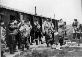 066_Ch_9_photo Aircrews gather outside the 'B' Flight office to await transport to take them to their aircraft, March 1943. Note the pigeons in their containers on the pathway, intended as an aid to air-sea rescue, and the varied flying gear | ©️Vincent Holyoak