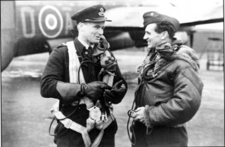 070_Ch_9_photo Twenty-four year old F/Lt Jack Sullivan (left) from Queensland talks to F/Sgt 'Freddie' Wilmot following their return from a raid, Spring 1943. Wilmot and his crew failed to return from Dusseldorf in June, whilst the Sullivan crew were lost whilst attacking Milan in August | ©️Vincent Holyoak