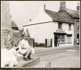 Vivian and Shirley Wright of Barkstone-le-Vale on the steps of The Market Cross. To the right The Old White House, then A.E. Greaves' Shop, c.1948.