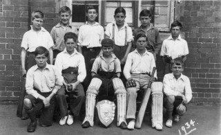 Bottesford School 1934 cricket team by the school building: the boys assembled for a group photograph in the school yard. | From the collection of Mrs Ada Bond