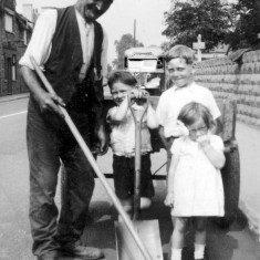 Bolland_0012_Joe___grandad_George_Jeff_and_Jean Joe (grandad) roadsweeping (being helped/hindered by George,Jeff and Jean).Randall's bus in the background.