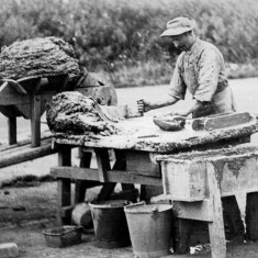 Picture 2.On the moulding bench the brickmaker is taking clay from the heap on the bench