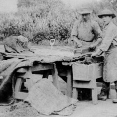 Picture 7. The surface is further smoothed with a 'strike', a moistened stick.. The boy dips another mould in the water trough to prepare it for the next brick.
