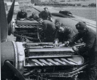 Ch_5_Photo_1 Engine fitters check over the two starboard Merlins of a 207 Squadron Lancaster on its Bottesford dispersal, summer 1942. In the distance are tents belonging to an A.T.C. summer camp. | ©️Vincent Holyoak