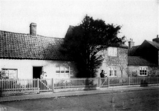 Norris family houses in the early 1900s - Nos 16 and 18 High St.  It shows Frank and Elizabeth Norris. They had twin sons Frank & John. Elizabeth is holding Frank and Frank is holding John