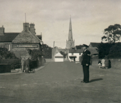 Sergeant Arthur Bradshaw on point duty in Bottesford around 1950, with St Mary's tower and spire in the background. The term 'holliers' refers to the parapet at the top of the tower, surrounding the base of the spire.