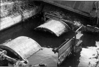 The remains of the arrester gear alongside Bottesford's main runway today. The two cable drums protrude from their water filled pit, with - to the right - the control panel | ©️Vincent Holyoak