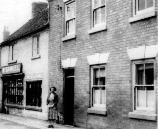 Samuels_crop Mrs. Samuels outside Samuel's 'Grocer and Draper'.