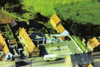 Standleys460 1960s aerial view showing Standley's Cottages and the recently built garage forecourt on the site of Hart's and of Ottley's shops. The cottages were demolished to create access from the High Street to the barns to the rear of the garage. These barns were then converted into a dwelling in the 1980s.