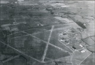 p_129 Bottesford from the air, looking north west, 1990. Although part of the main runway and the dispersals have long since gone, their 'ghosts' are still visible, as are the hangars and the classic 'A' shape of a wartime bomber airfield