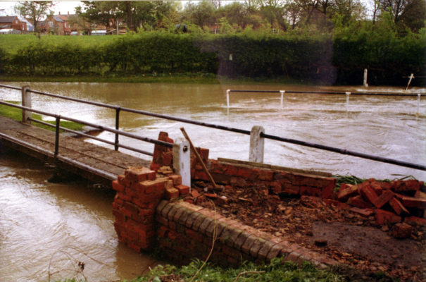 BOT025_019_MSA_flood_ca1980 Damaged footbridge at ford on Rectory Lane during flooding.