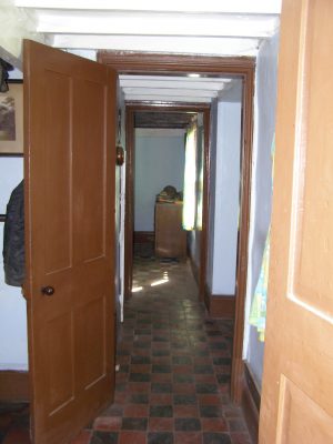 Looking from the dining-room through the passage and into the living room, showing the quarry-tile floor of these rooms and the beamed ceilings. | Neil Fortey