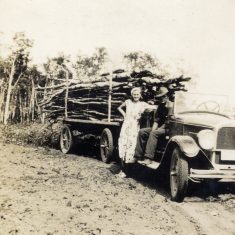 Hauling timber, a couple with their car and trailer piled high with lathes of timber. They may be Agnes and Victor Marston, self-sufficient in their Illinois home. | Janet Dammes