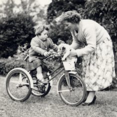 BOT177_068 Marston album3 07 'Mother loading up a pup for Janet to ride with, Providence rear lawn 1960.' | Janet Dammes