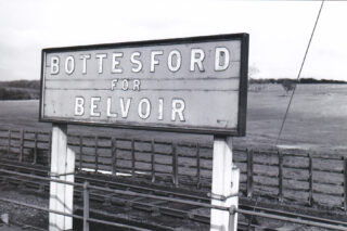 Bottesford for Belvoir - slide 1 'Bottesford for Belvoir' sign displayed on platform at Bottesford station, from an old postcard, date uncertain | Old postcard, photographer unknown