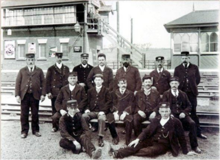 Bottesford for Belvoir - slide 38 Botteford's statiomaster, believed to be Richard Gaylard, surrounded by his staff. Looking towards the eastbound platform with the station signalbox and waiting room. The two signalmen watch from the top of the steps, and there is a gas platform lamp in front of the signal box. | Bottesford Local History archive