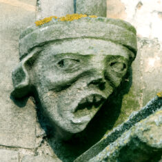 On the western gable of the north aisle, this face of terror is almost hidden behind the encroaching buttress of the tower. | Neil Fortey