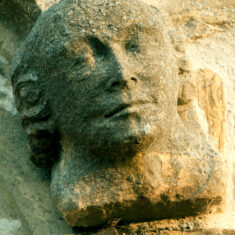 The second of two heads, probably both of men despite the long hair (perhaps a 17th Century hair style), at the ends of the hood mould of the north transept window, but seeming to be stuck on rather than an integral part of the structure, and thus later than the Perpendicular window itself. | Neil Fortey