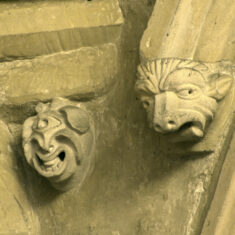 P1050375_04 The faces of a cyclops and a lion, between the rood-loft door and the chancel arch. The lion’s tongue is sticking out, suggesting a link to the lion carvings in the nave. | Neil Fortey