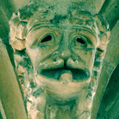 This head, possibly of an ape with long tresses, blackened malevolent eyes a toothless mouth and cleft palate. Attached to the lower lip is a disc-like object of uncertain significance, possibly a coin to pay for the soul's crossing across the Styx. | Neil Fortey