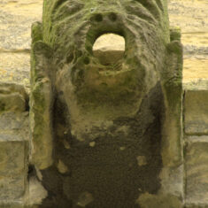 P1050504_03 One of the gargoyles on the tower, with mouths for water spouts: a man’s head clasped between his hands.