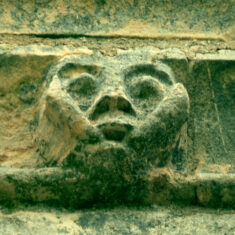 P1050505_06 One of the six small grotesque faces carved in the stones forming the frieze below the parapet of the tower.