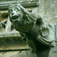 P1070372_04 On the south transept - The “alewife”: The eastern gargoyle: again, there is considerable detail, despite the centuries of exposure to the elements. She has a bowl in one hand, a jug in the other. Dating from the 15th Century, she may be announcing the church-ale. | Neil Fortey