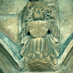 The roof of the nave is supported by stone corbels carved as angels, some holding scrolls, others holding shields. As with many of the other carvings mounted close beneath the roof, these have their eyes picked out in black paint, in these cases applied to the pupils rather than the whole eyes as in the case of the demonic carvings. | Neil Fortey